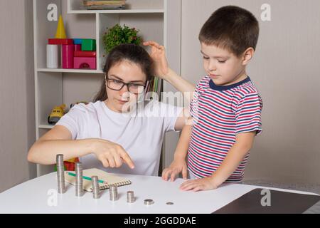 Il genitore insegna al bambino come maneggiare i soldi. Corso di alfabetizzazione finanziaria per bambini in età prescolare e scolastica. Foto Stock