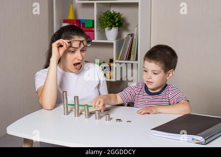 Madre e bambino imparano l'alfabetizzazione finanziaria per i bambini, per investire. Denaro, monete, crescita del reddito e acquisto di azioni. Foto Stock