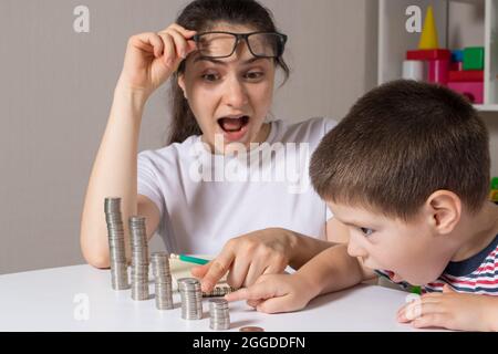 Il genitore insegna al bambino come maneggiare i soldi. Corso di alfabetizzazione finanziaria per bambini in età prescolare e scolastica. Foto Stock