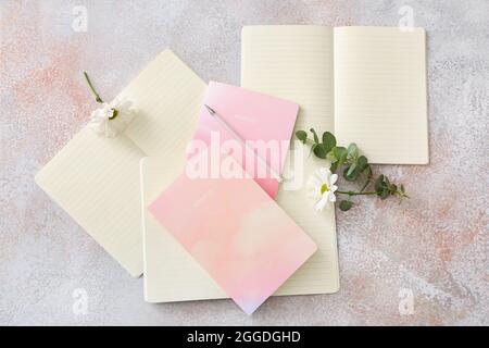 Composizione con taccuini, penna e fiore su sfondo grunge Foto Stock