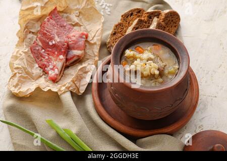 Pentola con gustosa zuppa di orzo di manzo su sfondo grunge Foto Stock
