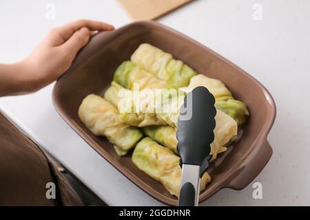 Donna che prepara gustosi involtini di cavolo ripieni in cucina, primo piano Foto Stock