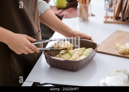 Donna che prepara gustosi involtini di cavolo ripieni in cucina, primo piano Foto Stock