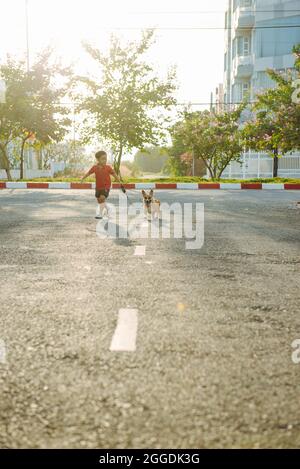 Kid boy corre sulla strada con il suo cane Foto Stock