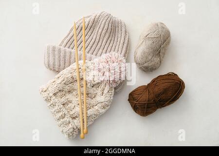 Cappelli caldi, filati in maglia e aghi su sfondo chiaro Foto Stock