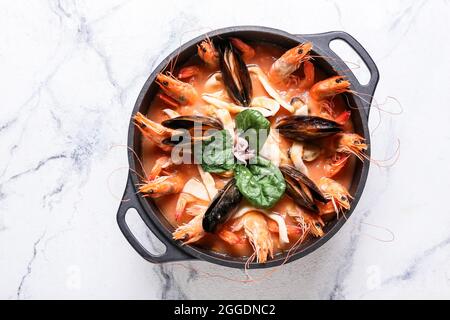 Pentola di gustosa zuppa di Cacciucco su sfondo chiaro Foto Stock