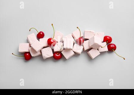 Gustose marshmallows dolci e ciliegie su sfondo chiaro Foto Stock