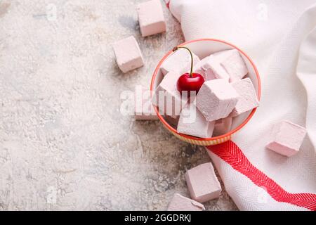 Ciotola con gustose marshmallows dolci e ciliegia su sfondo chiaro Foto Stock