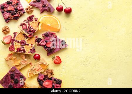 Tavolette di cioccolato fatte a mano con frutta e bacche su sfondo colorato Foto Stock