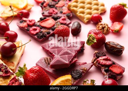 Tavolette di cioccolato fatte a mano con frutta e bacche su sfondo colorato Foto Stock