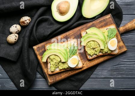 Avocado toast con guacamole e uova su sfondo di legno scuro Foto Stock