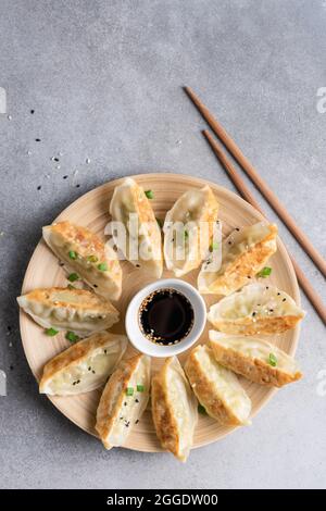 Jiaozi fritto o gyoza, gnocchi cinesi su piatto di bambù, vista dall'alto Foto Stock