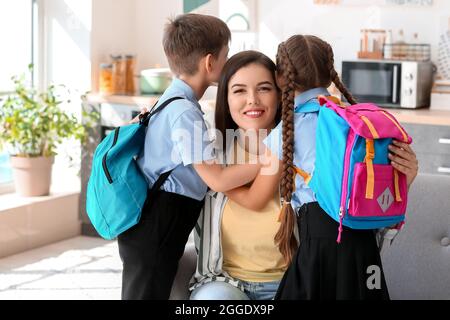 Madre che dice Arrivederci ai suoi bambini piccoli prima della scuola Foto Stock