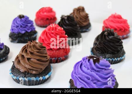 Vivaci cupcake di colore marrone, rosso e viola Foto Stock