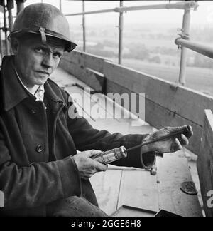 Un lavoratore che carica una pistola rivettatrice durante la costruzione di due silos di zucchero presso la fabbrica di barbabietole da zucchero Poppleton. Laing costruì due silos di zucchero per la British Sugar Corporation Limited presso la Poppleton Sugar Beet Factory. Sono state progettate per contenere un totale di 16,000 tonnellate di zucchero ed erano le più grandi ad essere state costruite nel paese quando questa foto è stata scattata. I silos prestressati di calcestruzzo post-tensionato sono stati realizzati con casseri scorrevoli utilizzando martinetti idraulici da arrampicata. Foto Stock