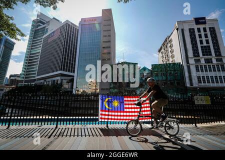 Un ciclista passa davanti a una bandiera malese durante le celebrazioni del 64esimo giorno nazionale a Kuala Lumpur.Malaysia celebrando il suo 64esimo giorno di indipendenza ogni anno il 31 agosto, commemora la Dichiarazione di indipendenza malese del 31 agosto 1957. (Foto di Wong Fok Loy / SOPA Images/Sipa USA) Foto Stock