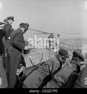 Un gruppo di membri del personale della RAF sul tetto della Cattedrale di Coventry che guardano un elicottero belvedere della RAF che si avvicina alla cattedrale. La fotografia è stata scattata durante l'operazione Rich Man, un progetto congiunto che coinvolse il personale dell'Aeronautica reale e il personale di Laing. Questo ha coinvolto un elicottero belvedere RAF che si è issato per posizionare la guglia di bronzo da 80 piedi sulla nuova cattedrale. La parte dell'operazione di abbassamento della traversa di 1/2 tonnellate che si trova sulla sommità della guglia doveva essere posticipata a causa delle condizioni di vento. Foto Stock