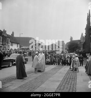 Una veduta della Regina Elisabetta II e del Vescovo di Coventry sul marciapiede fuori dalla Cattedrale di Coventry il giorno del servizio di consacrazione, con fotografi della stampa e folle che guardano dallo sfondo. Questa immagine è stata catalogata come parte del Breaking New Ground Project in collaborazione con il John Laing Charitable Trust nel 2019-20. Foto Stock