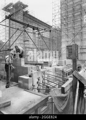 Una vista del cantiere della Cattedrale di Coventry, che mostra due costruttori che costruiscono un muro in primo piano e ponteggi eretti intorno alla conchiglia dell'edificio sullo sfondo. Questa immagine è stata catalogata come parte del Breaking New Ground Project in collaborazione con il John Laing Charitable Trust nel 2019-20. Foto Stock