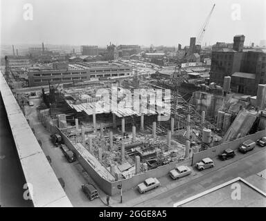 Una vista dal tetto dell'edificio della Società cooperativa in Dantzic Street, guardando a nord-est sopra il cantiere per l'edificio della Società cooperativa di assicurazione (CIS), che mostra la costruzione della lastra al piano terra sopra la sezione profonda del seminterrato. La didascalia sotto la corrispondente stampa di questa immagine dice: "Colonne in primo piano pronte per ricevere soletta del pavimento sono state costruite da un tetto di riparo RAID aereo esistente. Le gru Weitz G60 e Buildmaster Tower sono in uso rispettivamente sopra il seminterrato profondo e le sezioni del tetto di riparo. Calcestruzzo mescolando pianta può essere visto a destra della foto Foto Stock