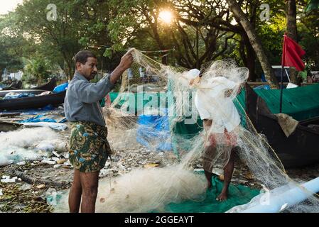 Kochi, India - 5 gennaio 2015: Reti da pesca cinesi e un pescatore in una barca che cattura il pesce a Cochin, backwaters in una giornata di sole in Kerala Foto Stock