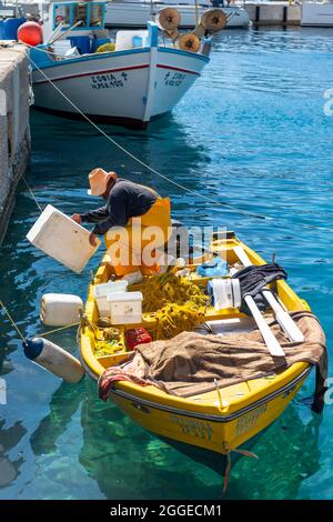 Pescatori su una piccola barca a remi nel porto di Livadia sull'isola di Tilos, Dodecaneso, Grecia Foto Stock