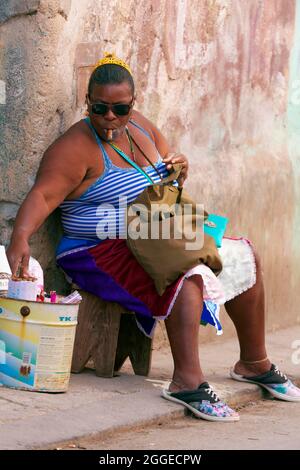 Donna cubana grassa, con pelle scura, cubana, seduta sullo sgabello davanti alla porta d'ingresso e sigaro fumante, Città Vecchia, capitale Avana, Provincia dell'Avana, Grande Foto Stock