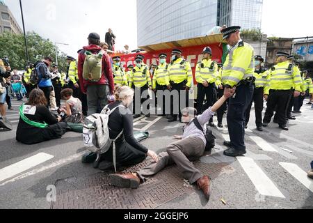 Polizia e dimostranti con un autobus parcheggiato sul London Bridge nel centro di Londra durante una protesta da parte dei membri della Rebellion di estinzione. Data foto: Martedì 31 agosto 2021. Foto Stock