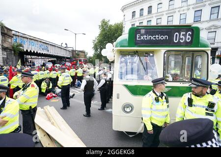 Polizia e dimostranti con un autobus parcheggiato sul London Bridge nel centro di Londra durante una protesta da parte dei membri della Rebellion di estinzione. Data foto: Martedì 31 agosto 2021. Foto Stock