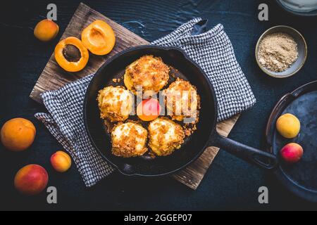 Gnocchi dolci con pangrattato dolce e ripieni di albicocche, albicocche fresche, sfondo nero, vista dall'alto Foto Stock