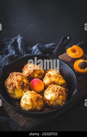Gnocchi dolci con pangrattato dolce, ripieni di albicocche, su sfondo nero, verticali con spazio di riproduzione Foto Stock