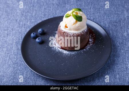 Torta di lava - torta al cioccolato fondente con gelato alla vaniglia, mirtilli e menta. Dolci francesi tradizionali. Primo piano. Foto Stock