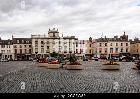 Fiori in fiore nei aiuole di cemento che adornano la Piazza di Kelso forniscono una piacevole esposizione contro le ciottolate scure per gli amanti dello shopping Foto Stock