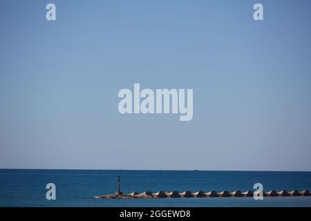 La mareggiata barriera frangiflutti. Blocco di calcestruzzo frangiflutti in porto. Paesaggio marino. Foto Stock