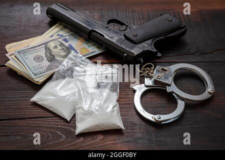 Droga narcotici possesso e uso, arresto e punizione per il concetto di business illegale. Pacchetti di plastica di cocaina, banconote in dollari USA a pistola e handcu Foto Stock