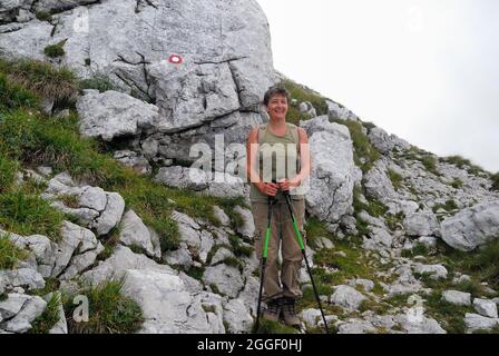 Slovenia, Monte Krn (monte Nero italiano). Lungo il sentiero per la cima si trova un'iscrizione sulla roccia : 'Monte Nero-Colletta Kozliack-2° Alpini 101^ Comp. Luglio 1916'. L'iscrizione è stata fatta dagli Alpini della Brigata Dronero, vicino al terminale del telpher che collegava la Sella Kodzljak con la prima linea italiana sul monte Krn. Una donna che cammina sale in cima. Foto Stock