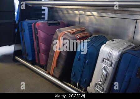 Molti tipi diversi di valigie e bagagli a mano nel bagagliaio del treno. I bagagli più grandi si tengono nello slot del treno Foto Stock