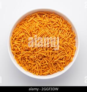 Primo piano di Alo Bhujia piccante in una ciotola bianca in ceramica, fatta con peperoncino rosso, patate e ceci. Spuntini speziati indiani (Namkeen), vista dall'alto Foto Stock