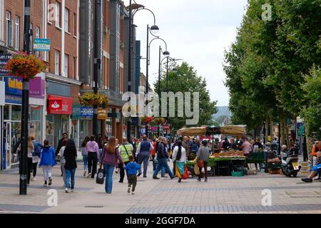 Bexleyheath Kent Inghilterra 08.31.21 persone si mescolano in una zona pedonale all'aperto per lo shopping. Negozio di facciate e cartelli. Bancarella del mercato vegetale. Righe di t Foto Stock