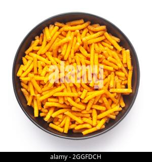 Primo piano di Nimbu masala besan Sv Indian namkeen (spuntini) su una ciotola nera in ceramica. Vista dall'alto Foto Stock