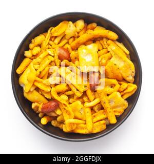 Primo piano di Gujrati Mix indiano namkeen (spuntini) su una ciotola nera in ceramica. Vista dall'alto Foto Stock