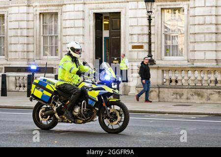 Londra, Inghilterra - Agosto 2021: Ufficiale di polizia su una moto con luci blu che lampeggiano guidando lungo una strada nel centro di Londra Foto Stock