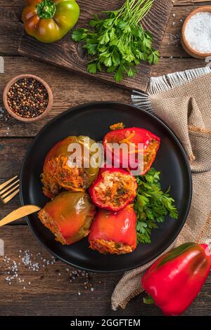 Un piatto con peperoni ripieni ed erbe su sfondo di legno. Foto Stock