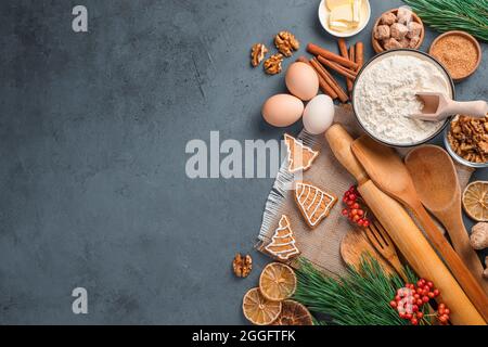 Ingredienti, utensili da cucina e biscotti allo zenzero su sfondo scuro. Vista dall'alto, spazio di copia. Foto Stock