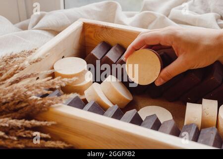 Prendere a mano sapone fatto in casa da scatola di legno pieno di shmpoo solido naturale e saponi Foto Stock