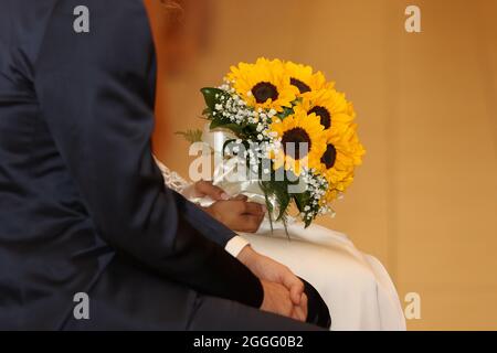 Coppia nuziale in chiesa con un bouquet di girasoli durante la cerimonia in chiesa Foto Stock