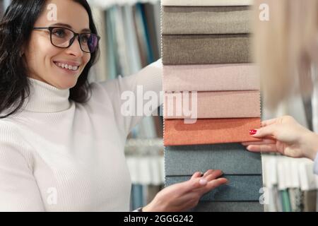 Venditore donna che mostra i campioni di tessuti dei clienti in negozio Foto Stock