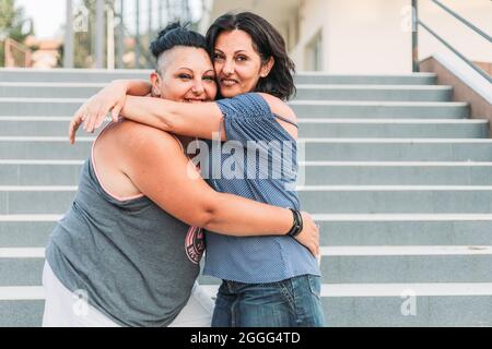 Due sorelle gemelle adulte abbracciano. Stili diversi Foto Stock