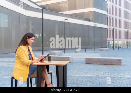 Donna d'affari caucasica che usa i pad mentre beve caffè all'aperto Foto Stock