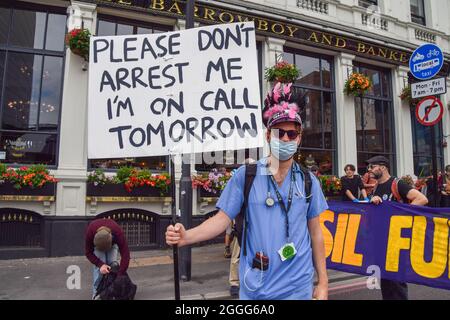 Londra, Regno Unito. 31 ago 2021. Un dimostratore che indossa un vestito medico tiene in mano una targhetta che dice "non arrestarmi sono in chiamata domani" durante la protesta.i manifestanti della ribellione di estinzione hanno bloccato le strade accanto al London Bridge con un autobus, come parte della loro campagna di ribellione impossibile di due settimane, Esortare il governo britannico ad agire in modo significativo sulla crisi climatica ed ecologica. Credit: SOPA Images Limited/Alamy Live News Foto Stock